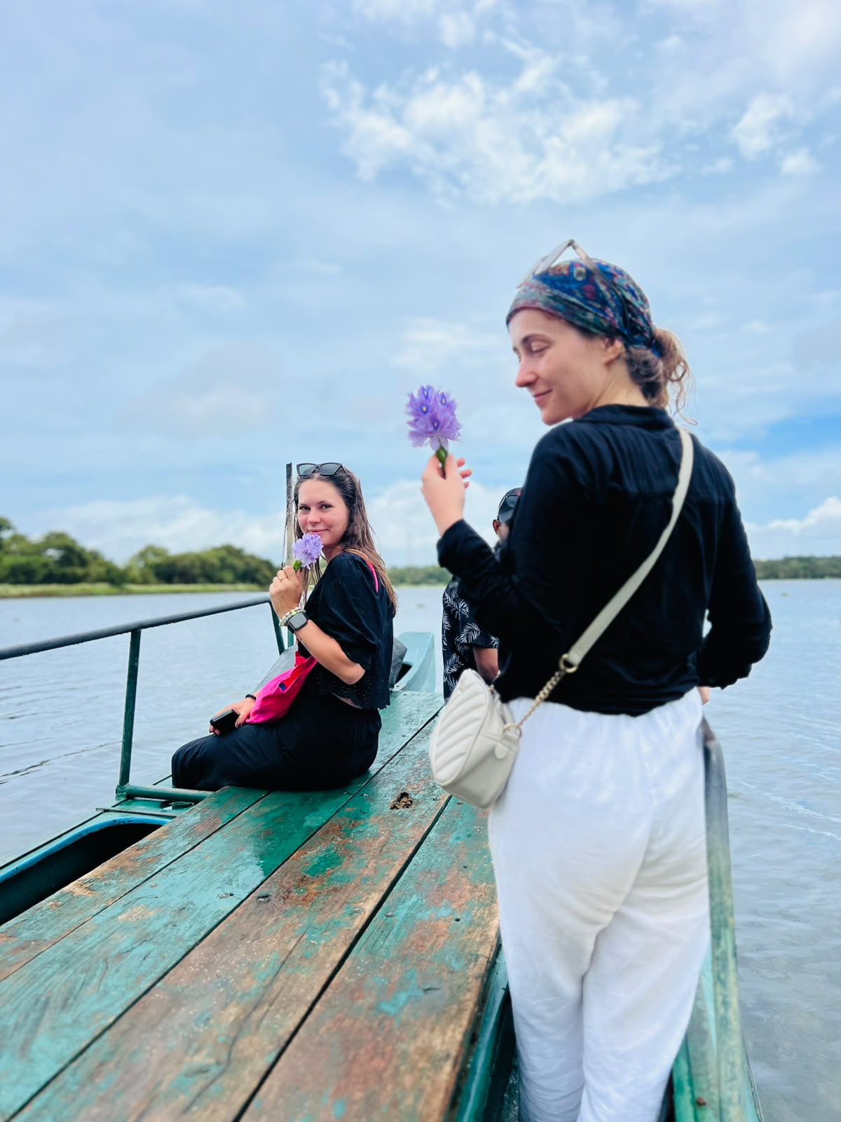 Guests enjoying a peaceful lake catamaran boat safari holding water lilies in Sri Lanka